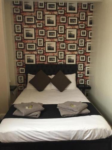 a bed with two pillows and a wall with pictures at Queens Guesthouse Manchester in Manchester