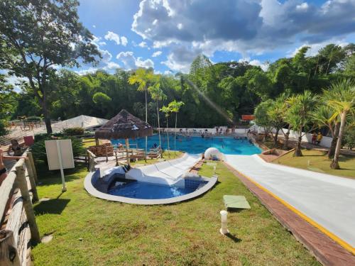 une piscine dans un complexe avec des arbres en arrière-plan dans l'établissement Araras Apart Service Caldas Novas, à Caldas Novas