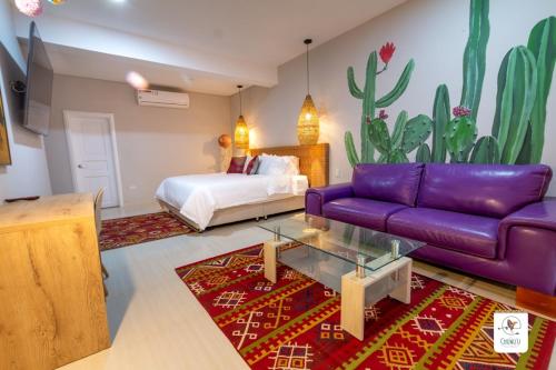 a living room with a purple couch and a bed at Hotel Boutique CASA CHUNUU Santa Marta in Santa Marta