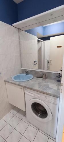 une salle de bain avec une machine à laver et un lavabo dans l'établissement Ancora- Appartement vue mer et place de parking, à Les Sables-dʼOlonne
