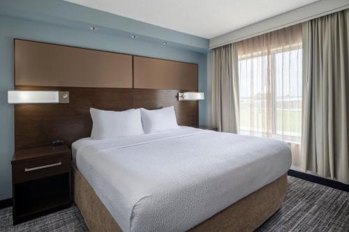 a large bed in a hotel room with a large window at Residence Inn by Marriott Bloomington in Bloomington
