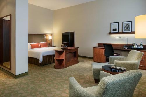 a hotel room with a bed and a tv and chairs at Courtyard by Marriott Bremen in Bremen