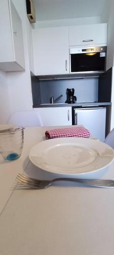 une plaque blanche et une fourchette sur un comptoir de cuisine dans l'établissement Marinas 2 - Agreable studio face au port Olona, à Les Sables-dʼOlonne