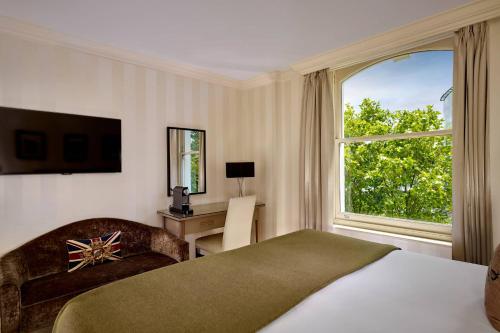 a bedroom with a bed and a desk and a window at Hotel Xenia - Autograph Collection in London