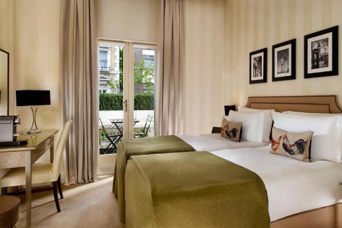 um quarto com uma cama, uma secretária e uma janela em Hotel Xenia - Autograph Collection em Londres