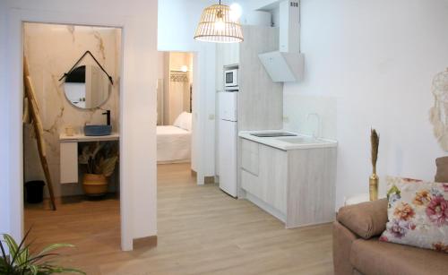 cocina y sala de estar con sofá y espejo en Apartamentos turísticos La Estación, en Úbeda