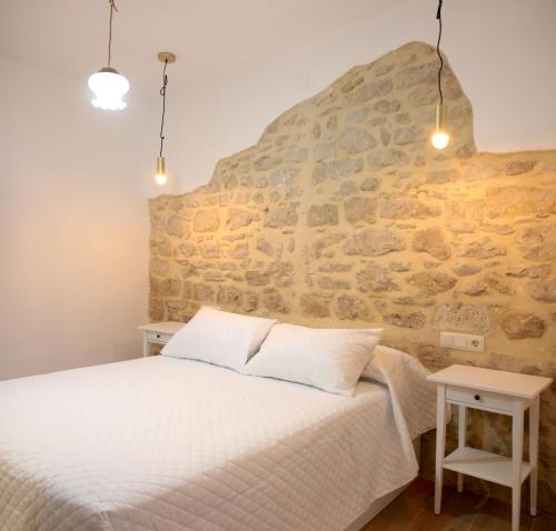 1 dormitorio con cama y pared de piedra en Apartamentos turísticos La Estación, en Úbeda