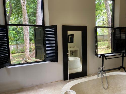 a bathroom with a bath tub and two windows at Galle Henna Estate in Unawatuna