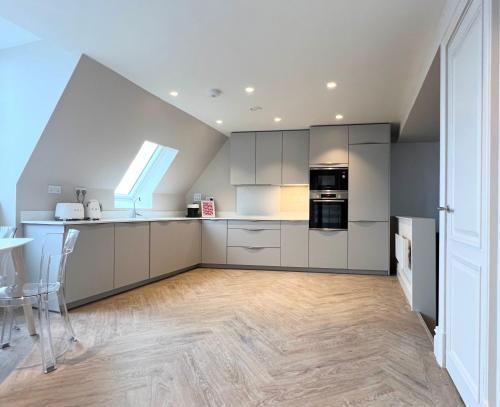 a kitchen with white cabinets and a table in it at The Apartments Lytham Square in Lytham St Annes