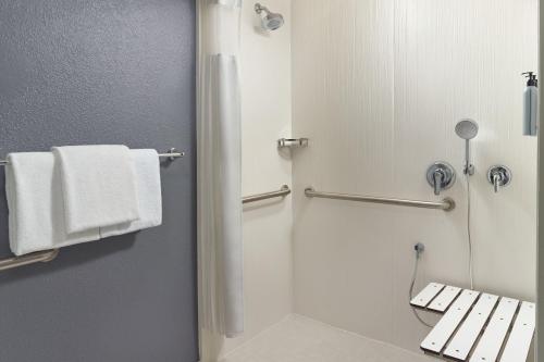 a bathroom with a shower and a toilet with towels at Courtyard by Marriott Tallahassee Downtown/Capital in Tallahassee