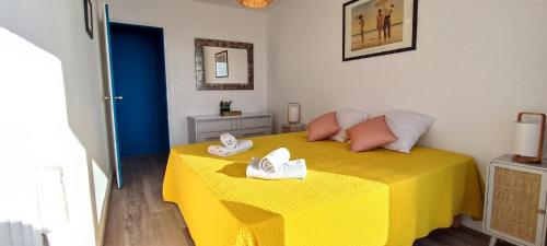 a bedroom with a yellow bed with towels on it at MIREILLE - Appartement 4 etoiles vue mer - 2 a 4 pers in Les Sables-dʼOlonne