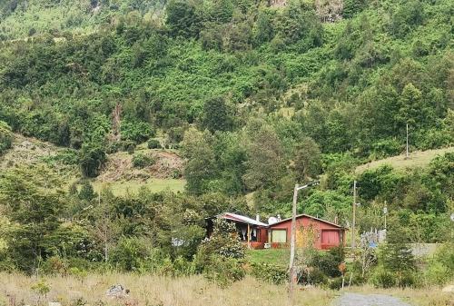 a small red house on the side of a mountain at Cabañas Piukewen in Riñinahue