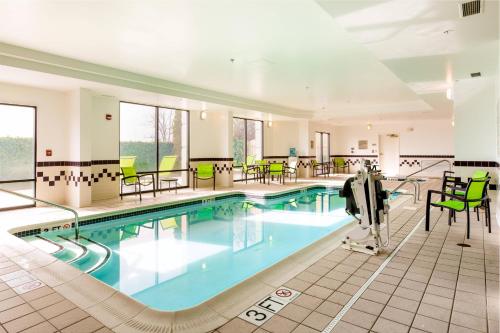 a pool in a hotel with green chairs and tables at SpringHill Suites Florence in Florence