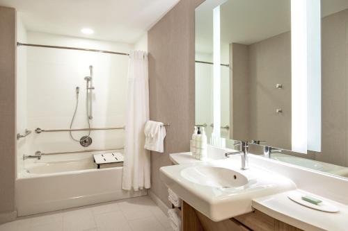 a white bathroom with a sink and a tub and a sinkonnaissance at SpringHill Suites by Marriott Boston Logan Airport Revere Beach in Revere