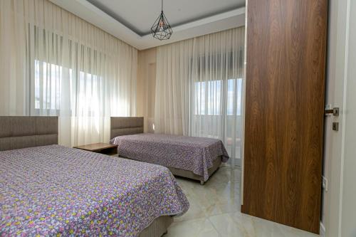 a bedroom with two beds and a sliding glass door at Paradise Town Villa Belhamra in Belek