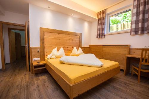 een slaapkamer met een groot bed met een houten hoofdeinde bij Apparthotel Panorama in Flachau