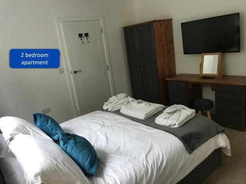 a bedroom with a bed with blue pillows and a television at Ocean View Apartments in Looe