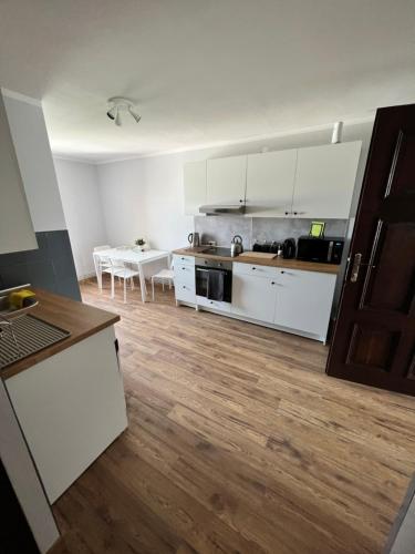 cocina con armarios blancos y suelo de madera en Nocleg Opole Kopernik Apartament, en Opole