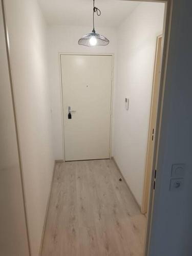 korytarz z białymi drzwiami i drewnianą podłogą w obiekcie Superbe studio en résidence neuve w mieście Chapelle-Saint-Mesmin