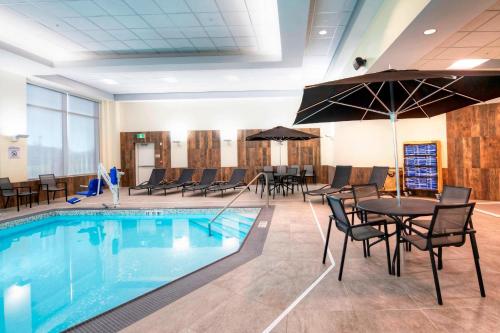 a pool with tables and chairs and a table with an umbrella at Fairfield Inn & Suites by Marriott Ottawa Airport in Ottawa