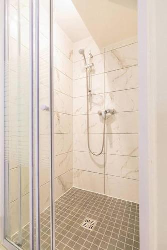 une douche avec une porte vitrée dans une salle de bain dans l'établissement Le Manhattan Monkey :au coeur du centre historique, à Dijon