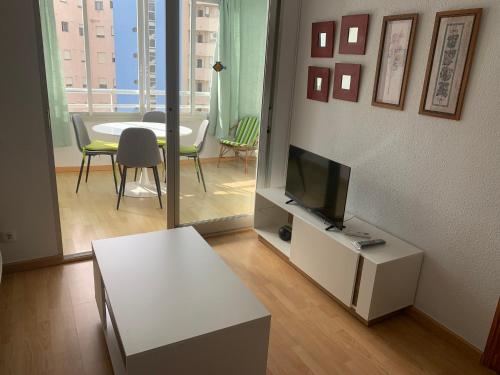 ein Wohnzimmer mit einem TV und ein Wohnzimmer mit einem Tisch in der Unterkunft SERVICE APART LAZARO- Apartamentos Aguamarina 58 in Calpe