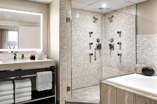 a bathroom with a shower and a tub and a sink at Los Angeles Airport Marriott in Los Angeles