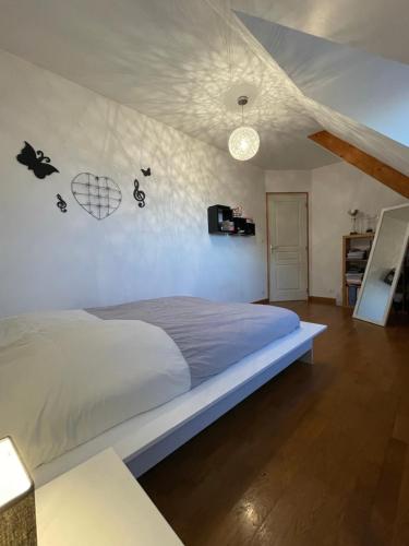 a bedroom with a bed and a white wall at Le Repaire des Bolides - 24H du Mans - 6p - Wi-Fi 