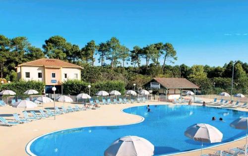 une grande piscine avec chaises et parasols dans l'établissement Chez Pauline et Pierre, à Soustons
