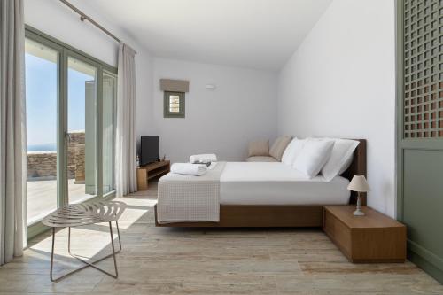 a white bedroom with a bed and a chair at Acron Andros - Luxury Villa with Private Pool in Andros