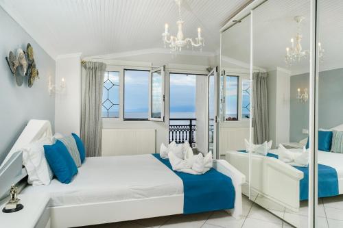 a white bedroom with blue and white furniture and windows at Villa Le Tresor in Skala Kallirakhis