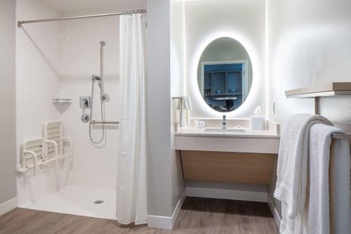 a bathroom with a shower and a sink and a mirror at TownePlace Suites By Marriott Milwaukee West Bend in West Bend