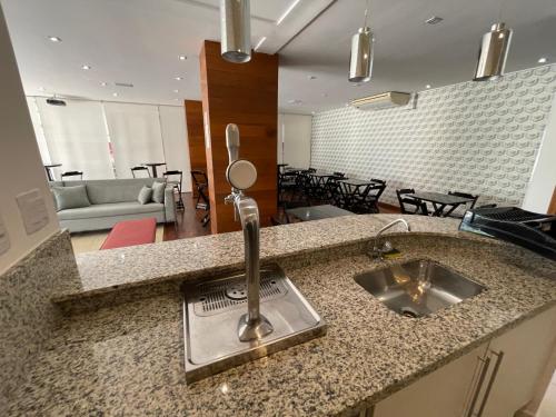 a kitchen counter with a sink and a living room at Apartamento familiar em Riviera de São Lourenço Módulo 8 in Bertioga
