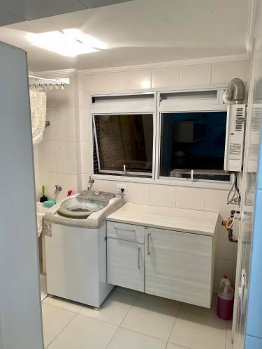 a white kitchen with a sink and a window at Apartamento familiar em Riviera de São Lourenço Módulo 8 in Bertioga