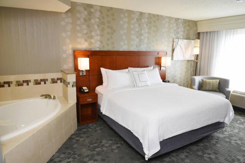 1 dormitorio con 1 cama, bañera, 1 cama y 1 cama en Courtyard By Marriott Sioux Falls, en Sioux Falls