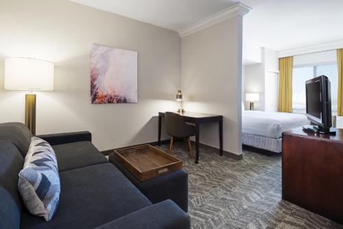 デンバーにあるSpringHill Suites by Marriott Denver Airportのソファとベッド付きのホテルルーム