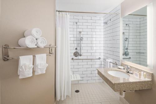 a bathroom with a sink and a shower with towels at SpringHill Suites by Marriott Denver Airport in Denver