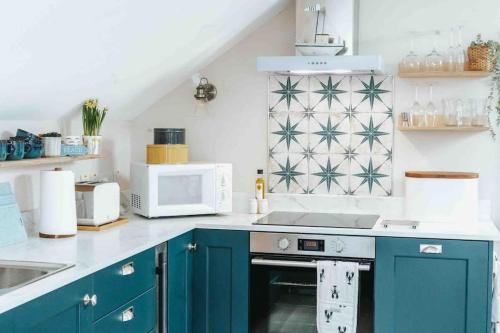 a kitchen with blue cabinets and a microwave at The Sea Loft Castlerock. in Castlerock