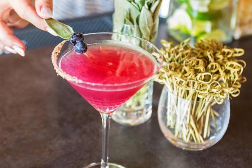 a person pours a pink drink in a martini glass at Mauna Kea Beach Hotel, Autograph Collection in Hapuna Beach
