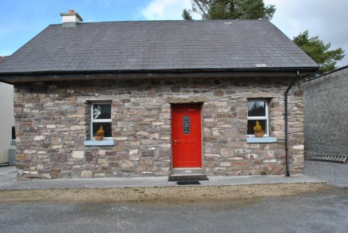 a small stone building with a red door and two windows at Douglas Lodge Holiday Homes in Keadew