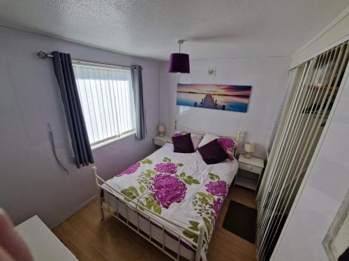 a small bedroom with a bed with purple sheets and a window at 60 upperlakeside glan gwna in Caernarfon