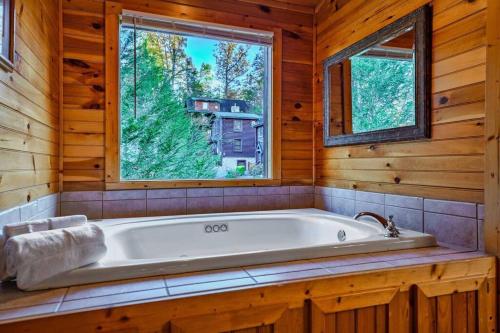 una vasca da bagno in una baita di tronchi con finestra di Stunning Mountain Cabin w/ Views a Gatlinburg