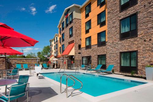 uma piscina num hotel com cadeiras e guarda-sóis em TownePlace Suites by Marriott Swedesboro Logan Township em Swedesboro