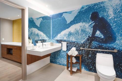 a bathroom with a painting of a man on a surfboard at Courtyard by Marriott Santa Monica in Los Angeles