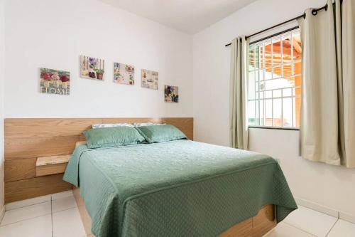 カボ・フリオにあるCasa de Praia com Piscinaのベッドルーム1室(緑の毛布、窓付)