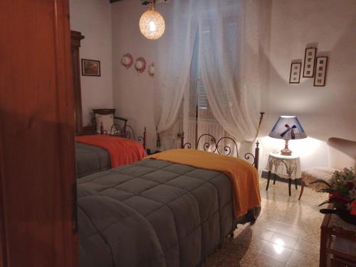 1 Schlafzimmer mit 2 Betten, einer Lampe und einem Fenster in der Unterkunft Casa Tarrini in Chianni