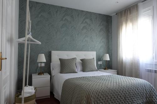 a bedroom with a white bed and a green wall at Céntrico y acogedor piso con garaje in A Coruña