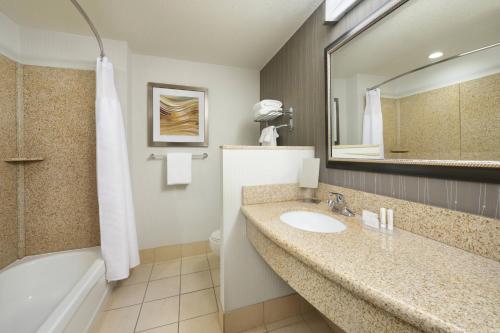 een badkamer met een wastafel, een bad en een spiegel bij Courtyard Grand Junction in Grand Junction