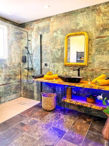 une salle de bain avec un lavabo et un miroir dans l'établissement love room Villa Des Charmes-34450 vias, à Vias