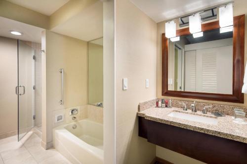 y baño con lavabo, bañera y espejo. en Newport Beach Marriott Bayview, en Newport Beach